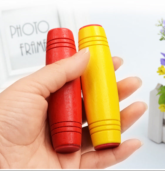 Hand holding red and yellow Mokuru fidget toys with a photo frame and flowers in the background